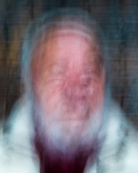 Portrait flou d'un homme âgé à barbe blanche sur fond sombre