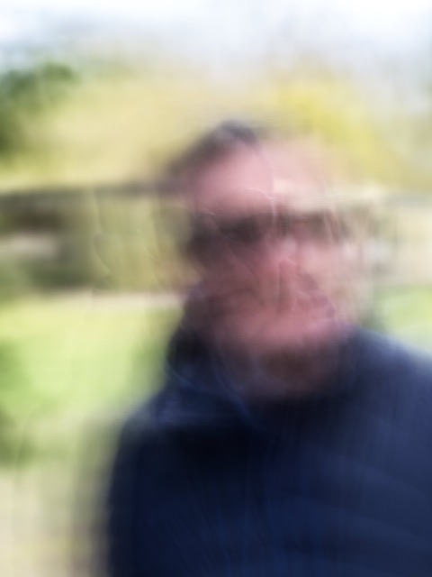 Homme à lunettes devant une barrière de campagne, visage en surimpression