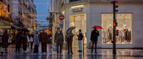 Passants aux parapluies devant une vitrine, rue de Paris sous la pluie