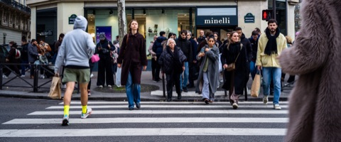 Foule sur un passage piéton, un homme en sweat gris à contresens