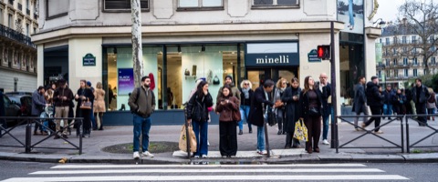 Piétons alignés au feu rouge devant une boutique, angle de rue parisien