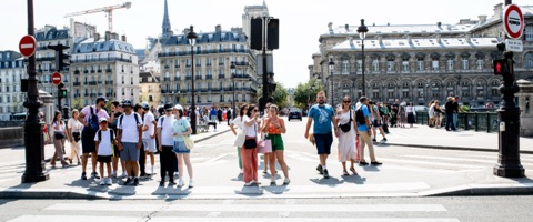 Groupe de touristes traversant un pont parisien en plein soleil d'été