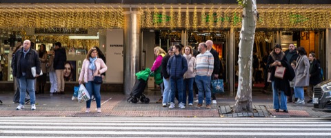 Passants devant une vitrine ornée de guirlandes dorées, période des fêtes