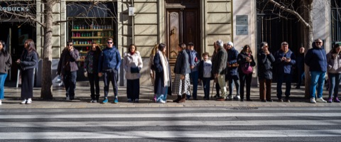 Piétons alignés dans la lumière rasante d'hiver, longues ombres sur le trottoir