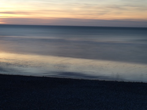 Plage de galets et mer lissée par la pose longue au crépuscule