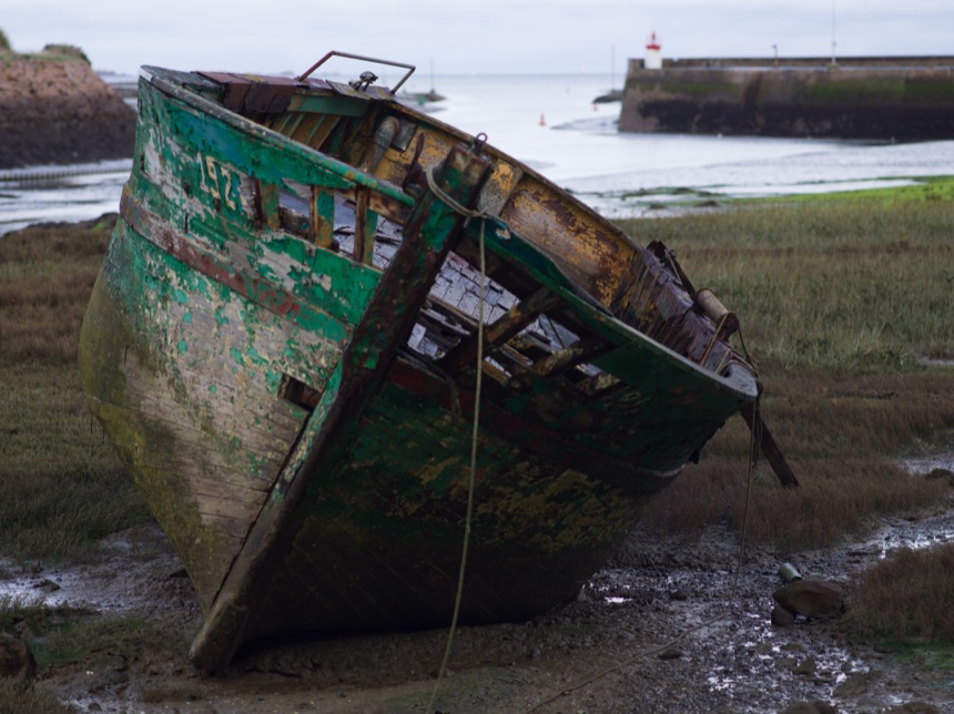 Épave de bateau de pêche vert échouée dans un port breton à marée basse